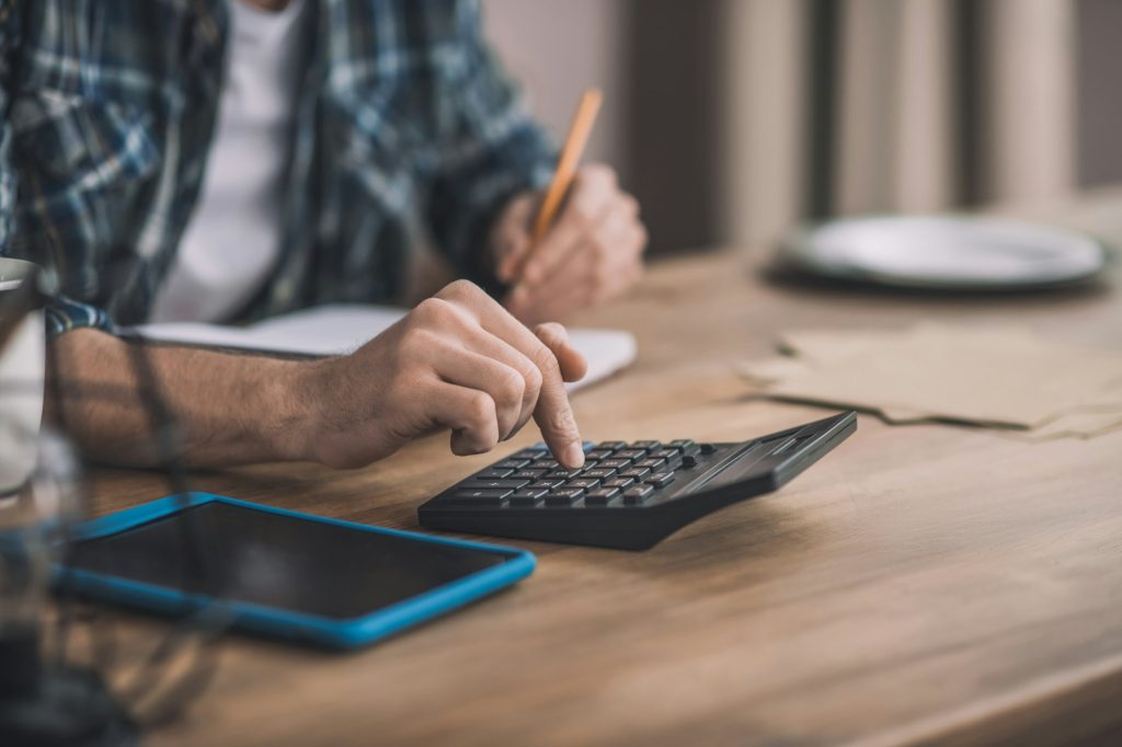 Man using a calc and other gadgets for financial estimation